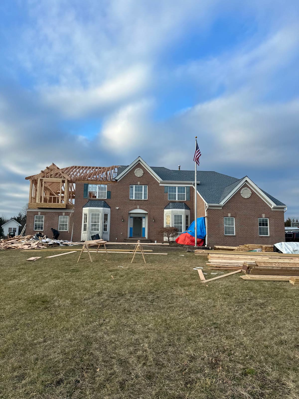 The front of the brick colonial with the new addition framed on the left