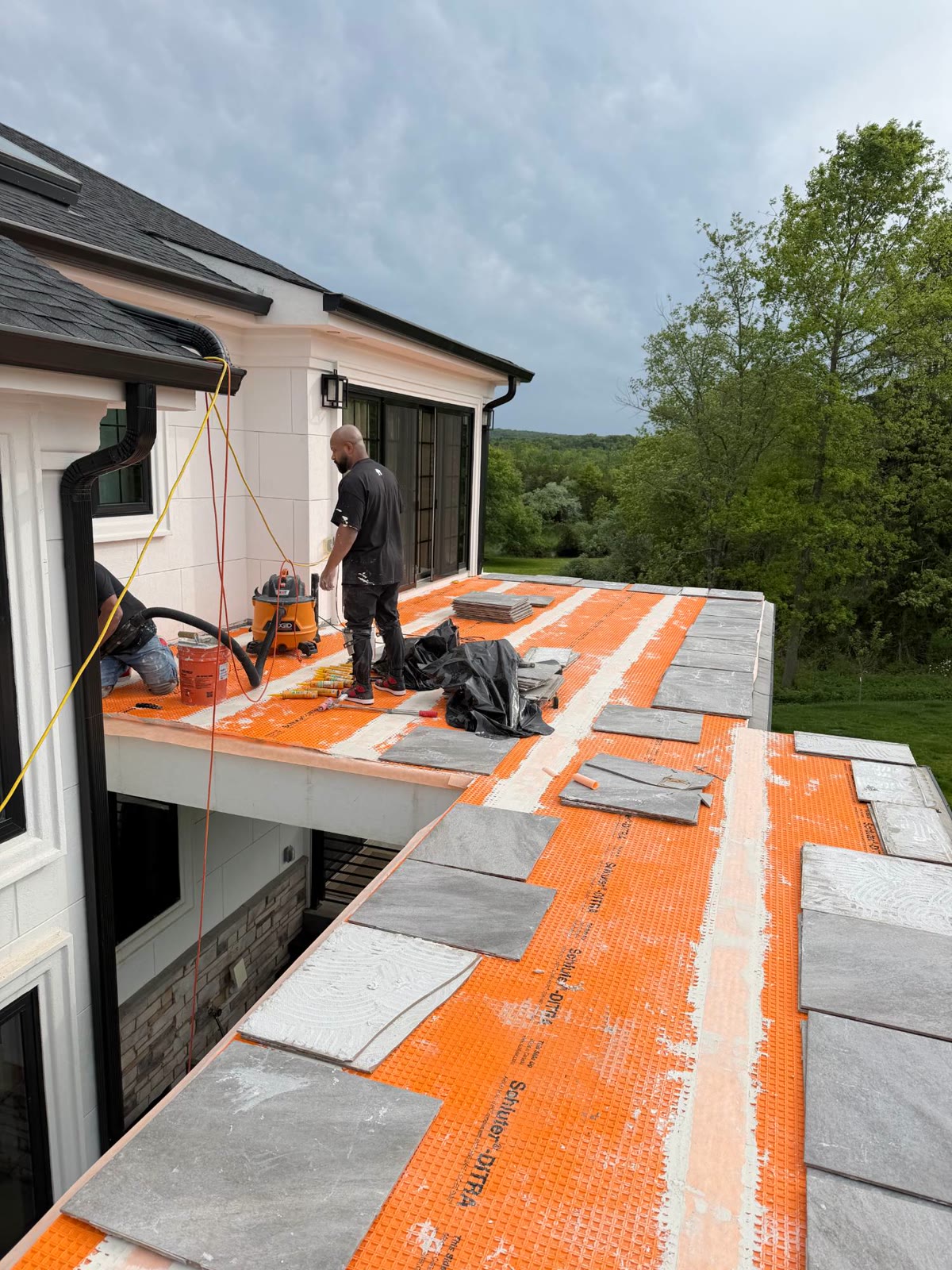 Crew setting porcelain tile on the upper balcony over a waterproofing membrane