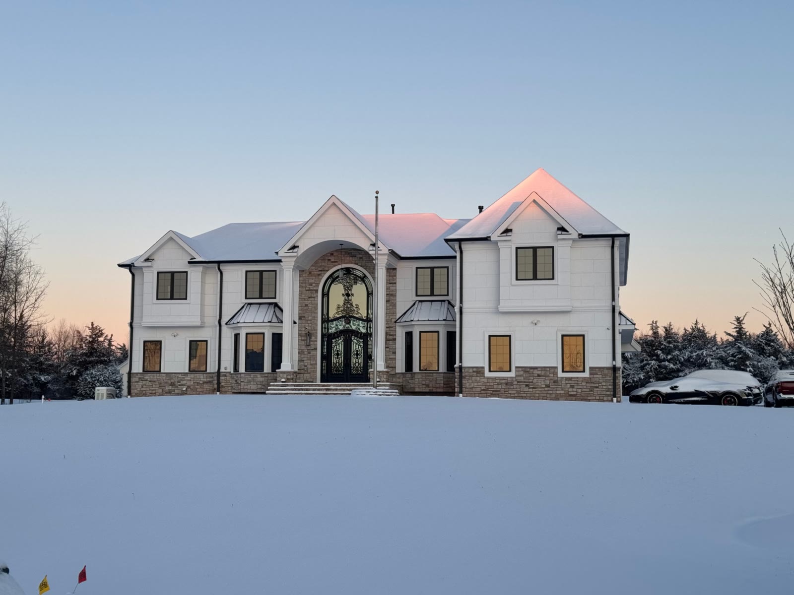 A finished Sum Builders residence with an arched iron entry, in fresh snow