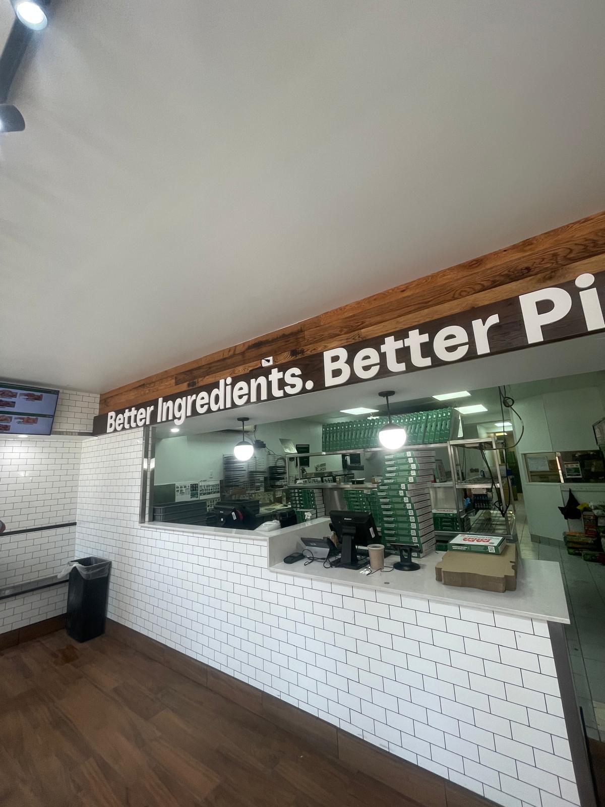 Service counter in white subway tile under a reclaimed wood header