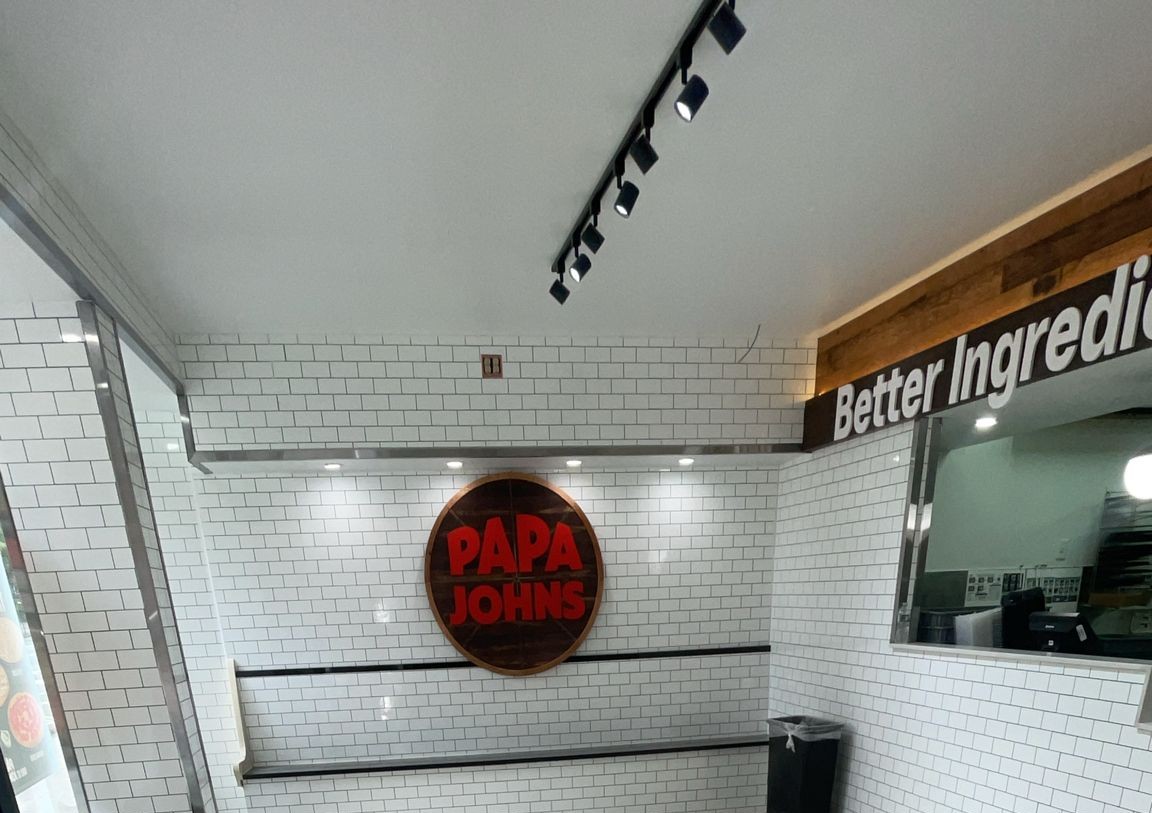 Logo wall in white subway tile with stainless trim and track lighting