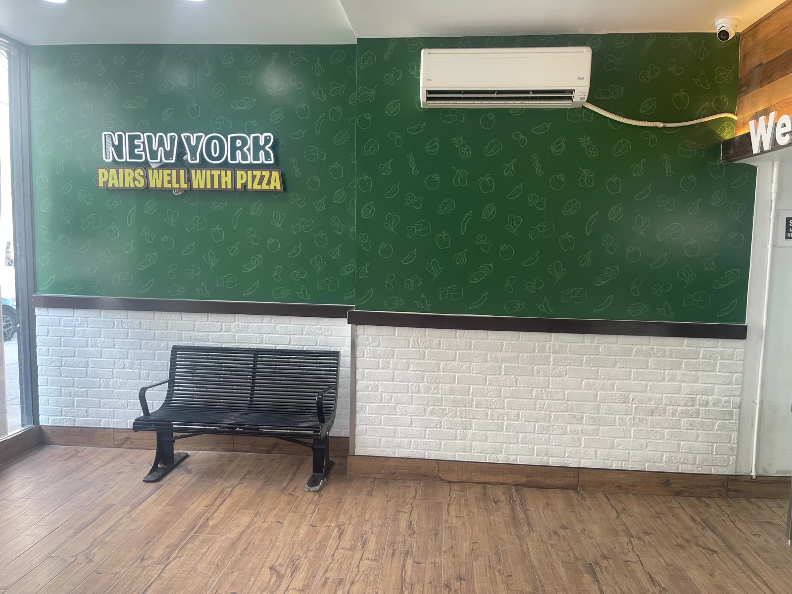 Green feature wall over white brick wainscot with a New York sign